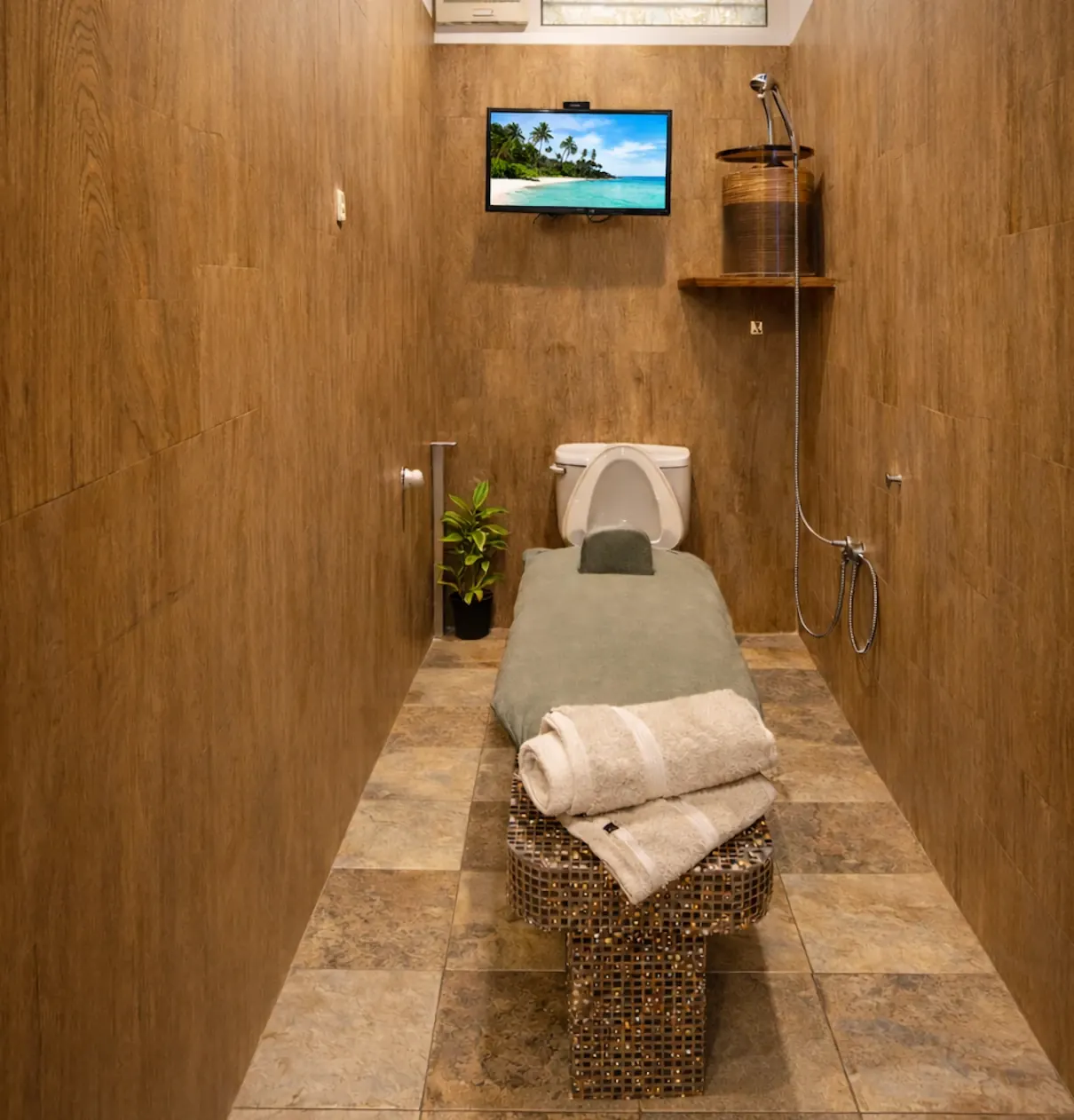 A private colema room: the colema board resting on a tiled bench, with the water container on the shelf above