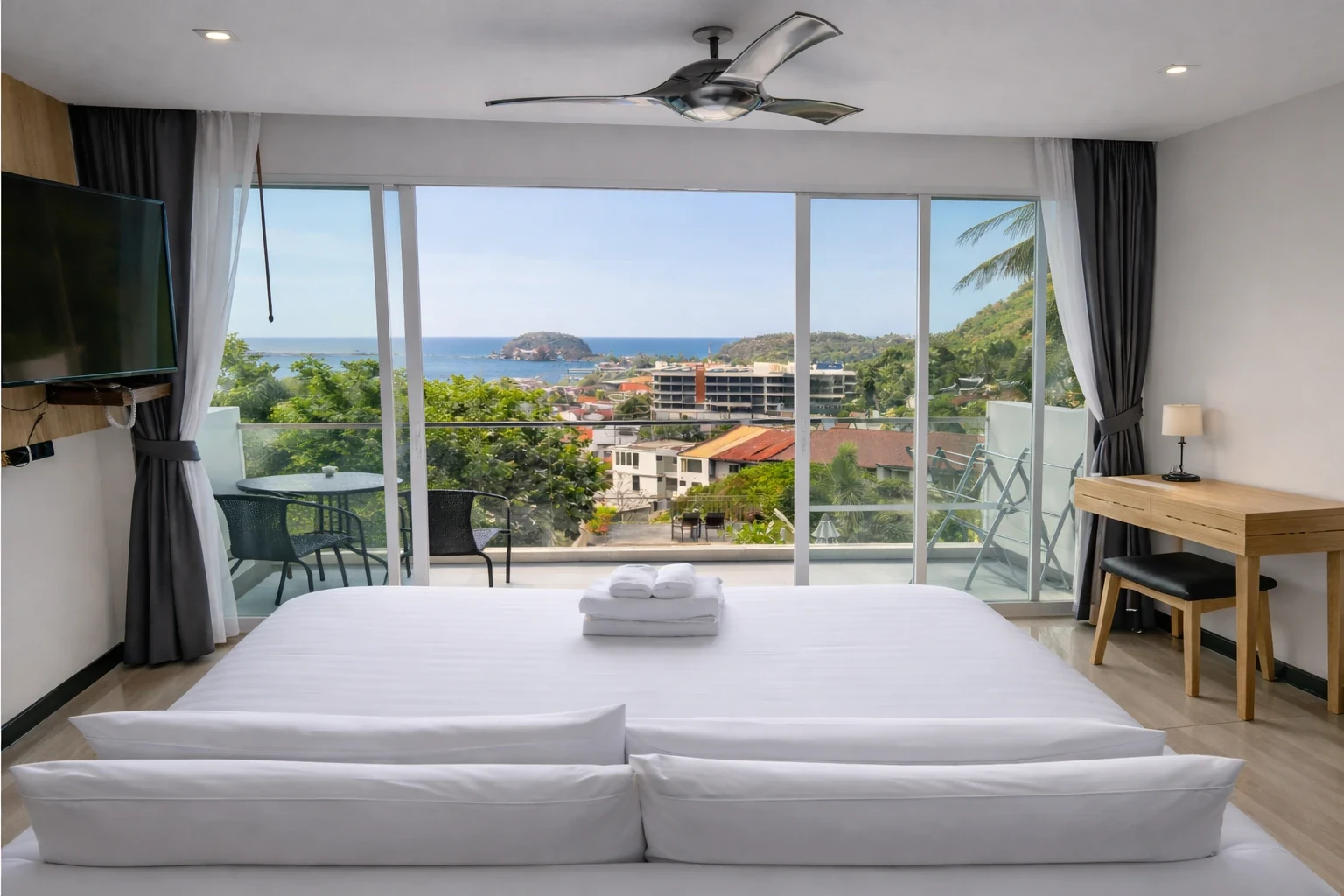 A sea-view room with the bed facing the balcony doors, open onto Kata Bay and the Andaman Sea