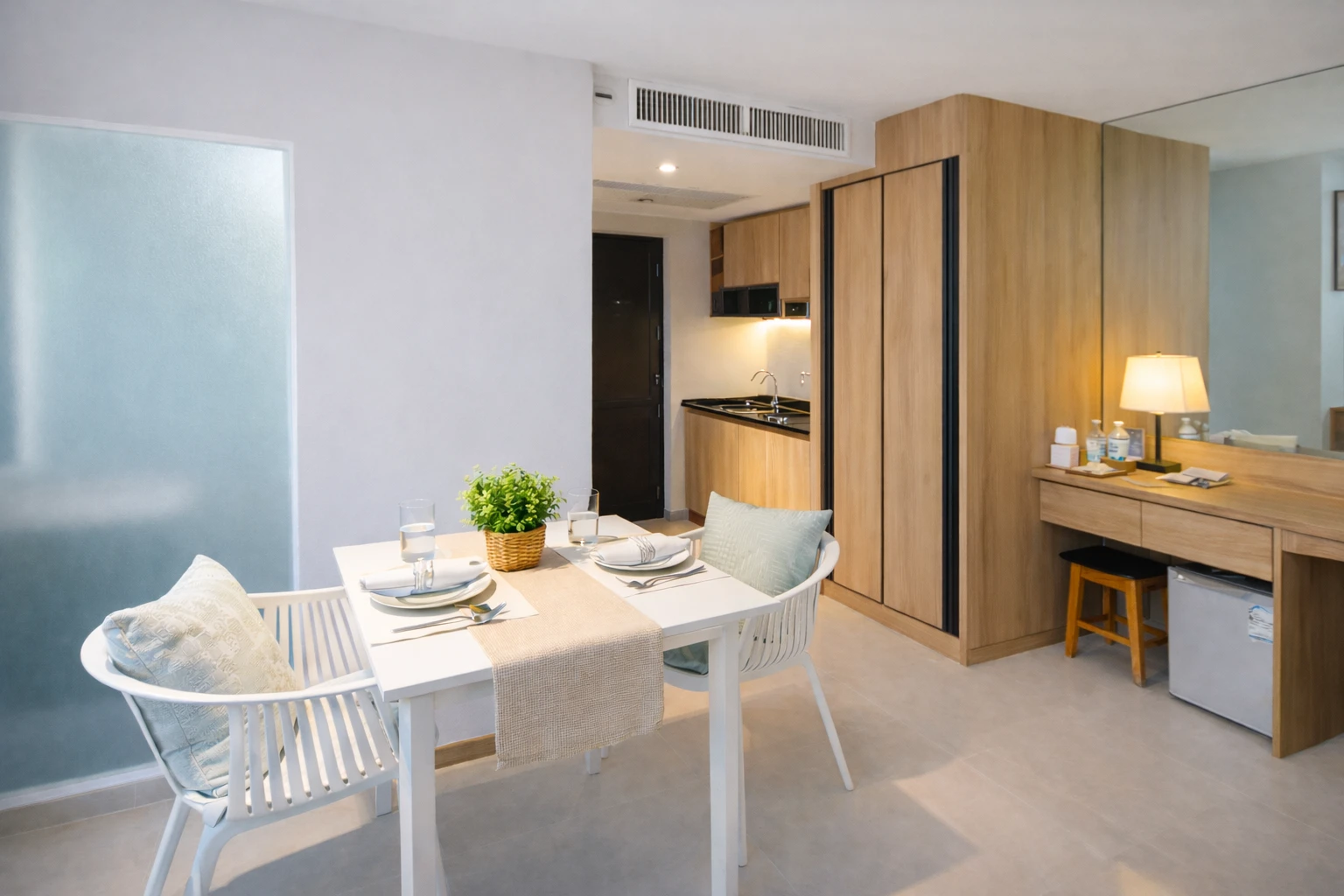 The dining table, with the kitchenette and wardrobe behind